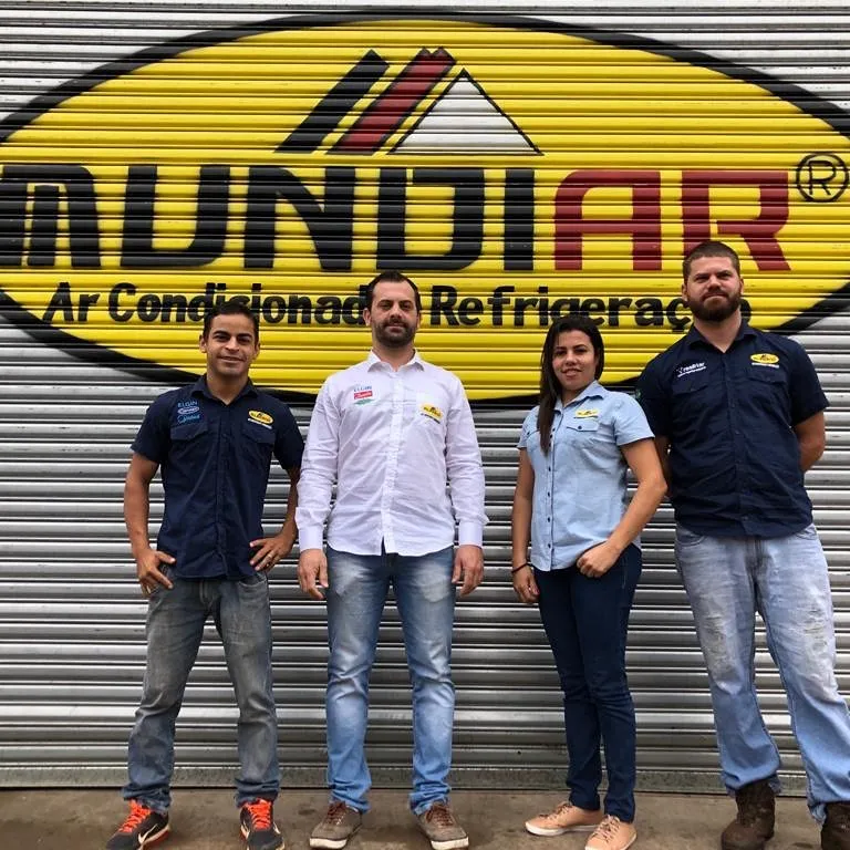 Equipe Mundiar uniformizada em frente à porta com o logotipo da empresa